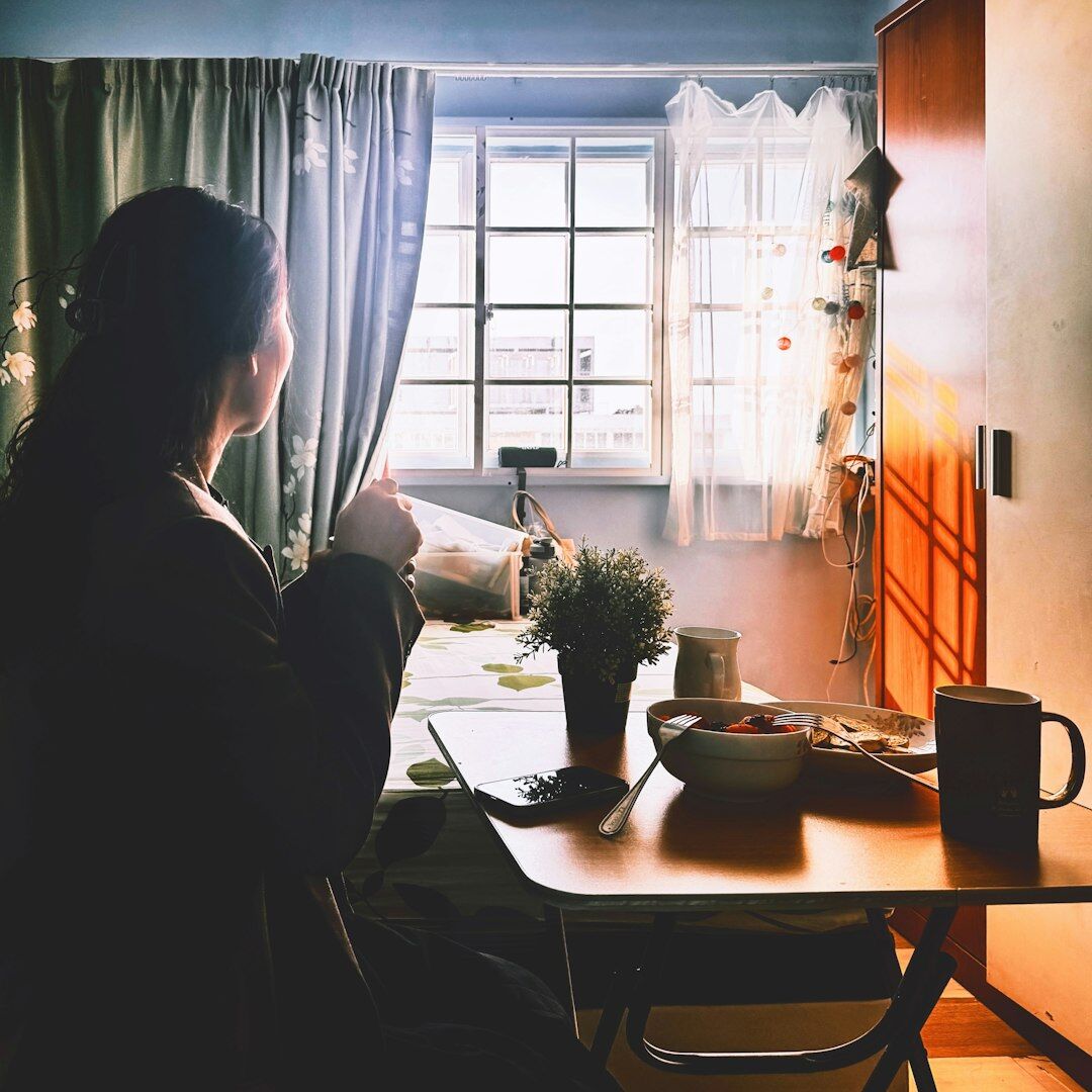 Woman writing notes while sitting by a window